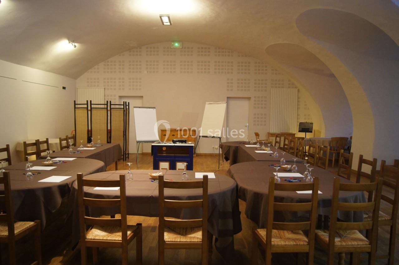 Salle de réunion avec tables ovales, chaises en bois, paperboards et matériel de présentation.