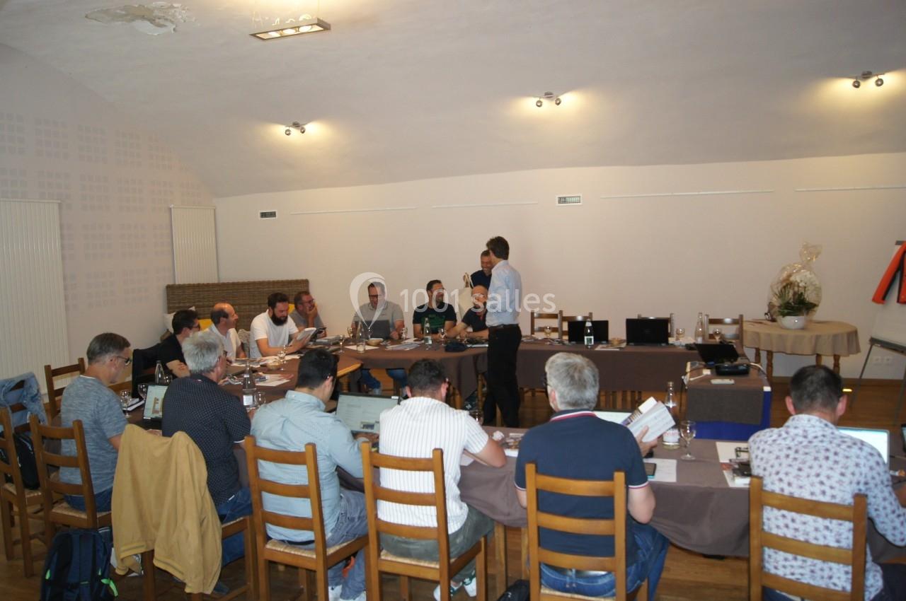 Un groupe de personnes assises autour d'une table en réunion dans une salle éclairée.