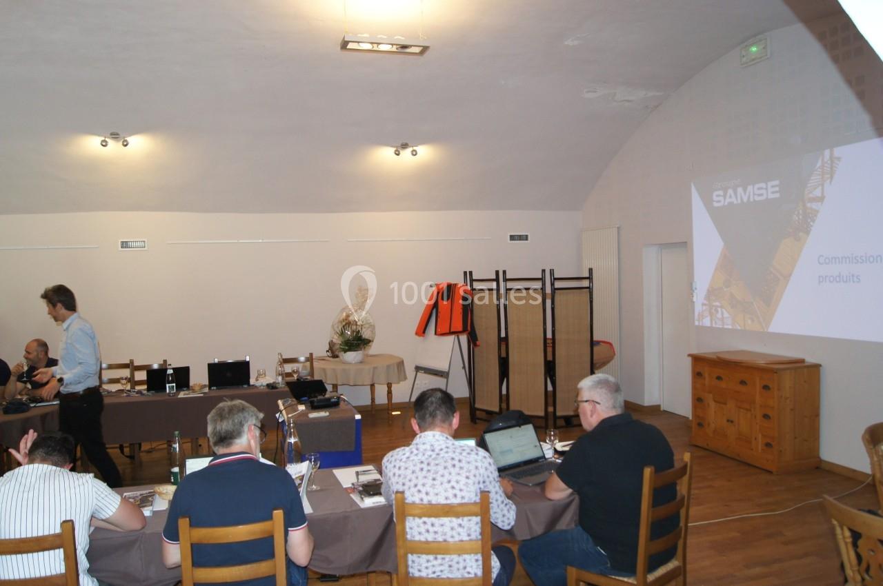 Des personnes assises autour d'une table lors d'une réunion, avec un projecteur affichant ’SAMSE Commission produits’.