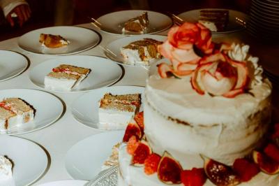 Arbuste dense à feuillage vert brillant à côté d'un arbre taillé, dans un jardin ensoleillé avec pelouse et végétation.