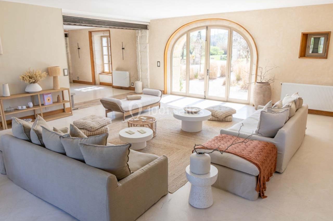 Salon lumineux avec canapés beiges, table basse ronde, grande baie vitrée et décoration minimaliste.