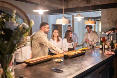 Arbuste dense à feuillage vert brillant à côté d'un arbre taillé, dans un jardin ensoleillé avec pelouse et végétation.