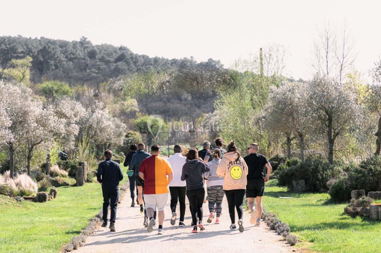 Un groupe de personnes court sur un chemin entouré de verdure et d'arbres par une journée ensoleillée.