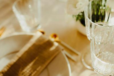 Arbuste dense à feuillage vert brillant à côté d'un arbre taillé, dans un jardin ensoleillé avec pelouse et végétation.