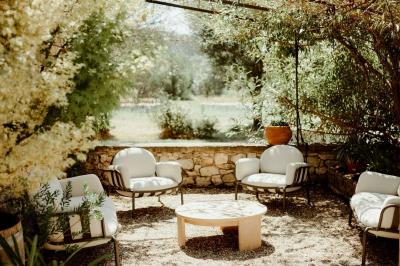 Arbuste à feuillage dense à gauche et arbre taillé à droite dans un jardin verdoyant sous un ciel clair.