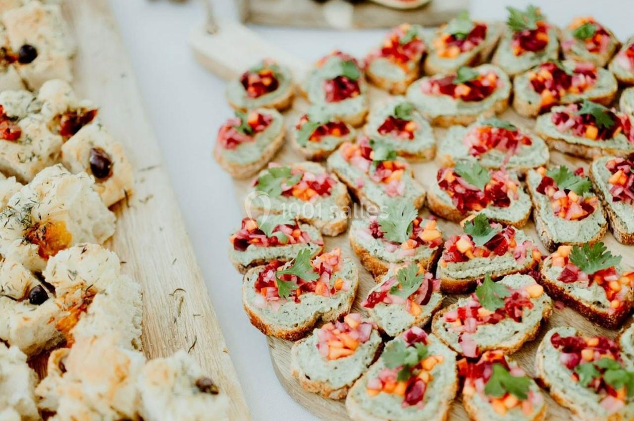 Plateau de toasts garnis de légumes colorés et herbes fraîches, disposés sur une table en bois.