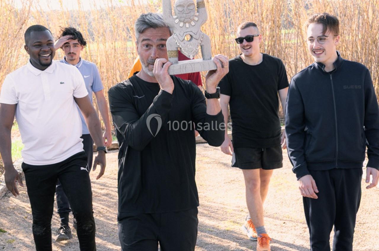 Un groupe de personnes marche en extérieur, l'une d'elles tient un trophée décoratif en forme de statue.