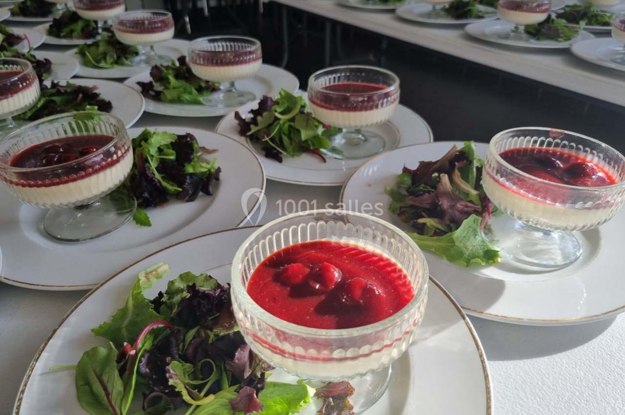 Assiettes dressées avec des verrines de dessert rouge et des portions de salade verte sur une table.