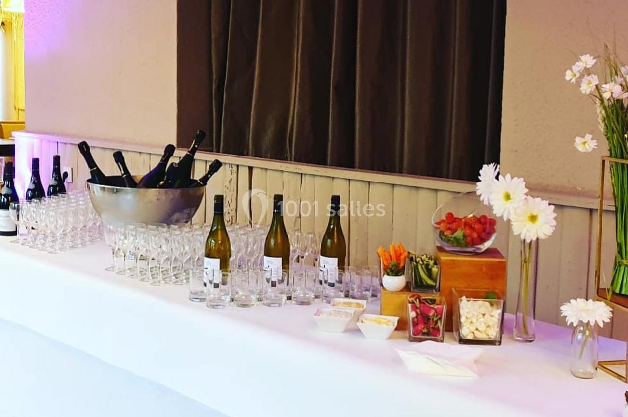 Table dressée avec des bouteilles de vin, des verres, un seau à champagne, des fleurs et des amuse-bouches colorés.