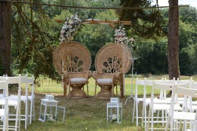 Centre de table floral avec roses roses, fleurs violettes et blanches, entouré de bougies et de verres sur une nappe blanche.