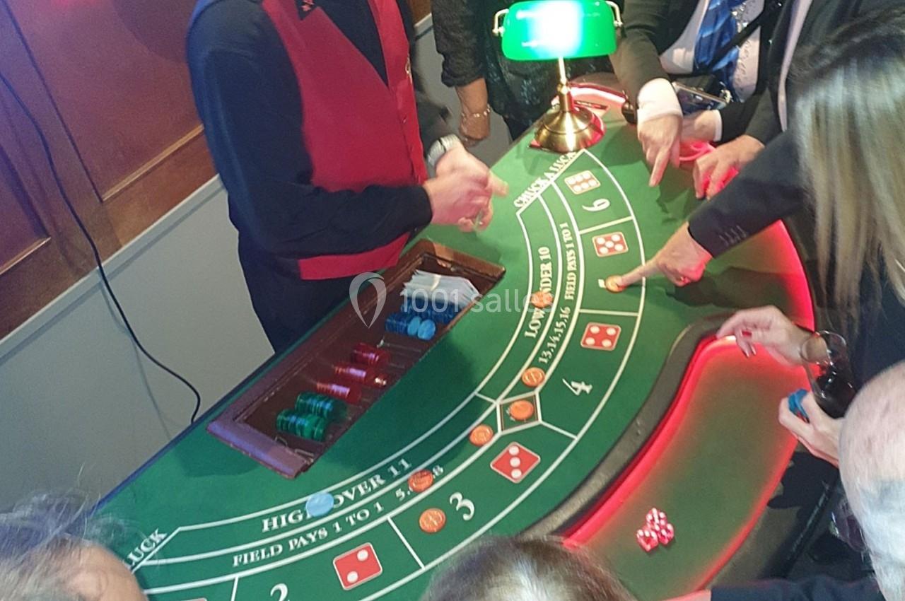Croupier animant une table de craps avec des joueurs pointant vers les dés et les cases de pari.