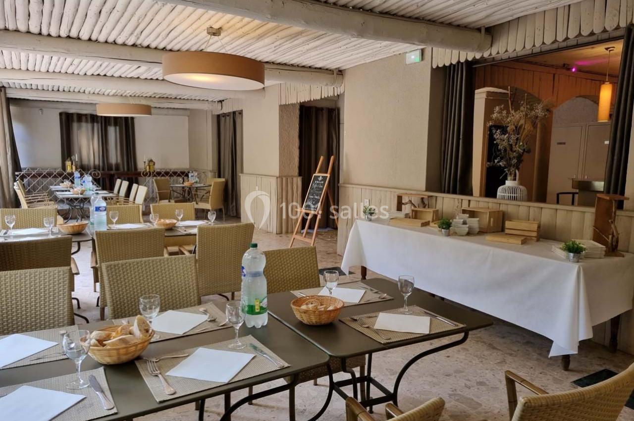 Salle de restaurant lumineuse avec tables dressées, chaises en osier, buffet décoré et ambiance chaleureuse.