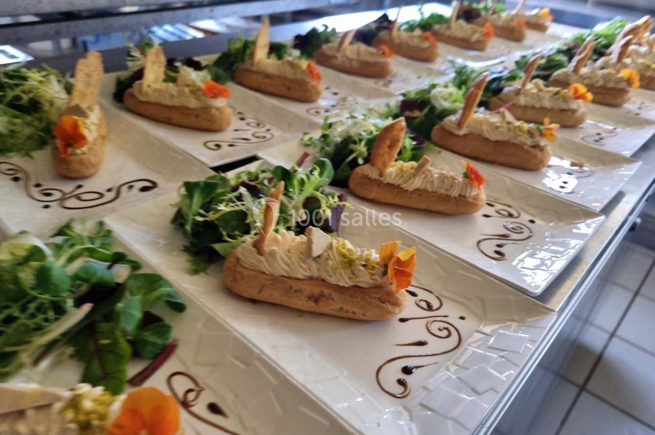 Assiettes dressées avec éclairs salés garnis, décorées de fleurs comestibles et accompagnées de salade verte.