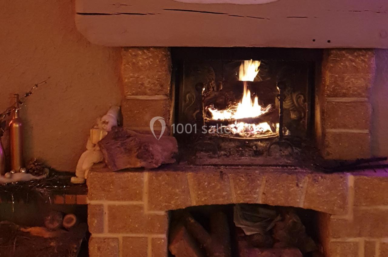 Cheminée en pierre allumée avec des bûches enflammées, entourée de décorations et d'objets rustiques.