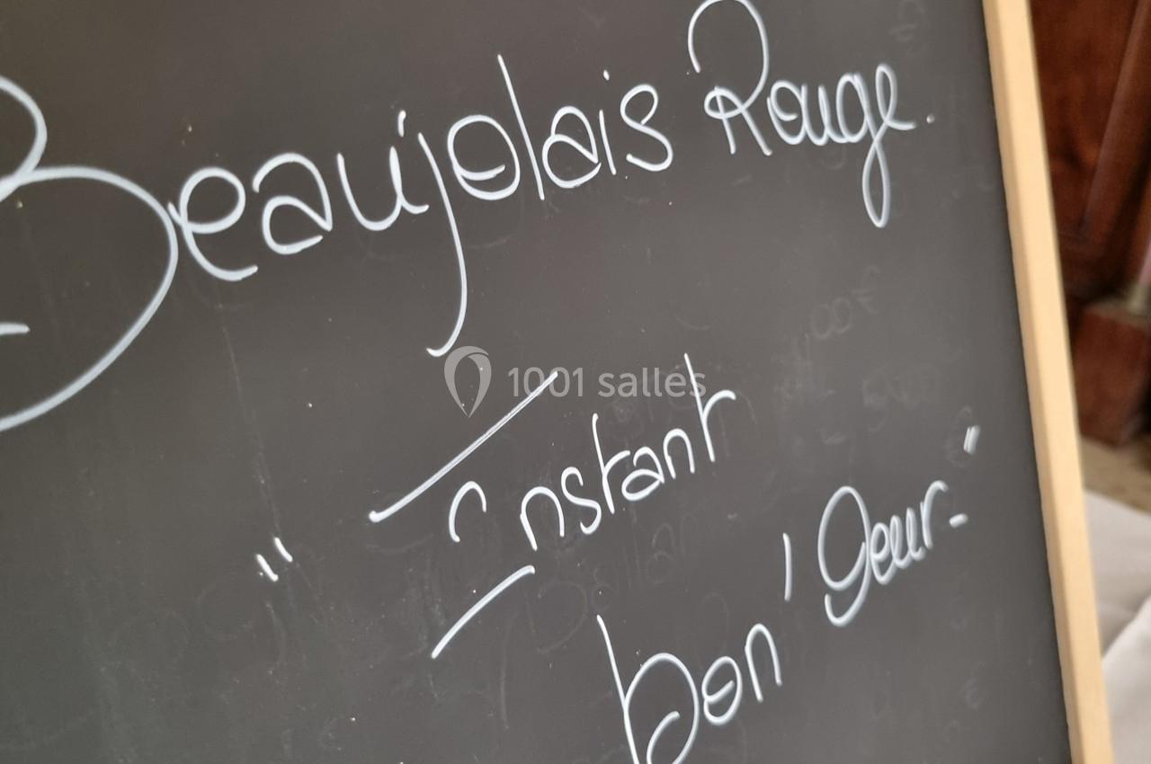 Ardoise avec l'inscription manuscrite ’Beaujolais Rouge’ et ’Instant bon'heur’ en lettres blanches.