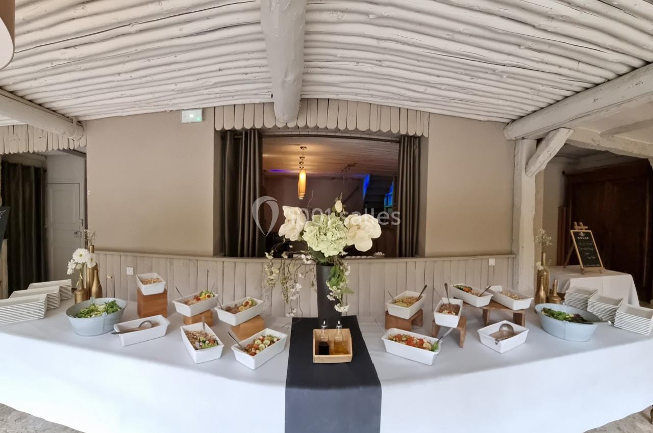 Buffet de salades et plats variés disposés sur une table blanche avec décoration florale au centre.