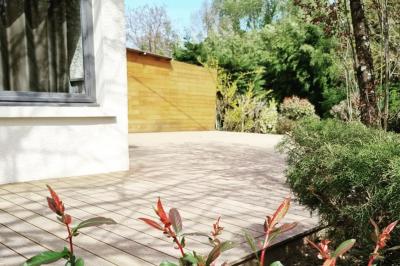 Vue aérienne d'une zone rurale avec des arbres, un cours d'eau sinueux et des bâtiments aux toits rouges.