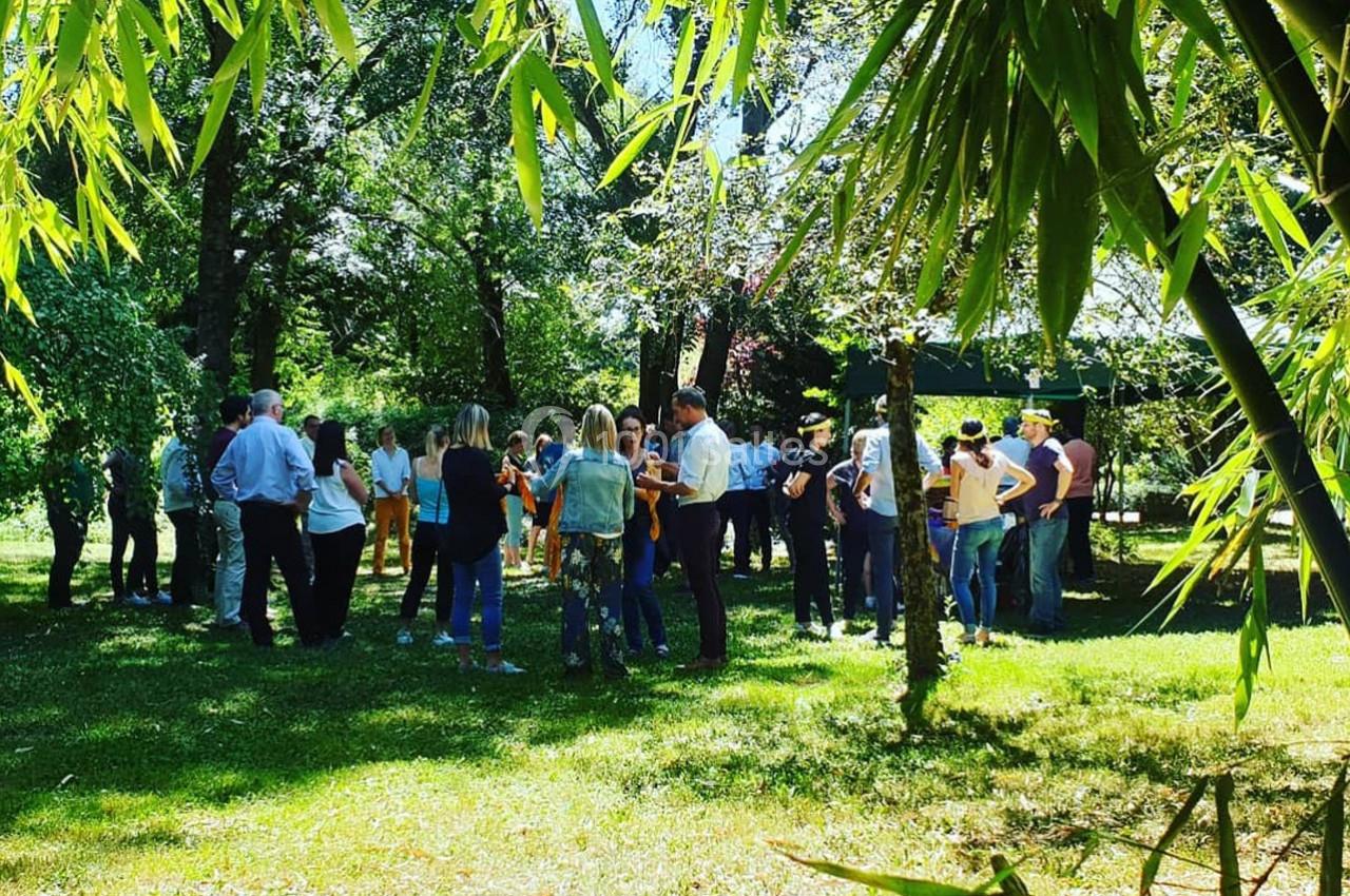 Un groupe de personnes discute dans un parc verdoyant, entouré d'arbres et de bambous, par une journée ensoleillée.