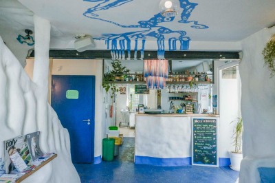 Intérieur d'un café avec un comptoir, des étagères de bouteilles, des murs blancs sculptés et une décoration bleue au…