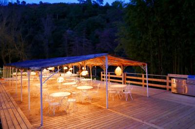 Table décorée pour un événement, avec nappes blanches, fleurs, bougies et couverts dorés dans un cadre extérieur.