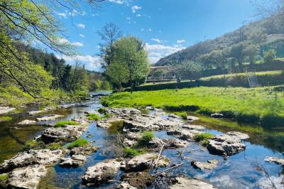 Table décorée pour un événement, avec nappes blanches, fleurs, bougies et couverts dorés dans un cadre extérieur.