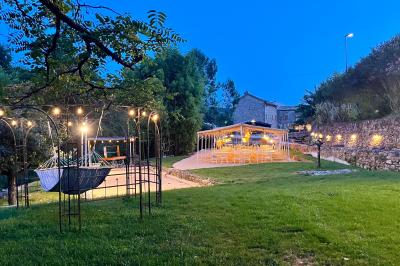 Rivière bordée de rochers et de végétation sous un ciel bleu, avec une maison partiellement visible en arrière-plan.