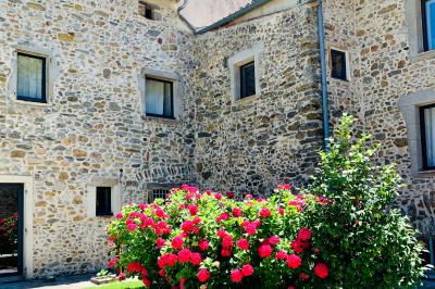 Rivière bordée de rochers et de végétation sous un ciel bleu, avec une maison partiellement visible en arrière-plan.