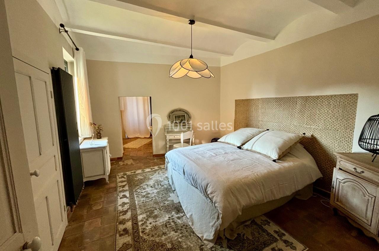 Chambre lumineuse avec lit double, mobilier en bois clair, tapis au sol et lampe suspendue au plafond.