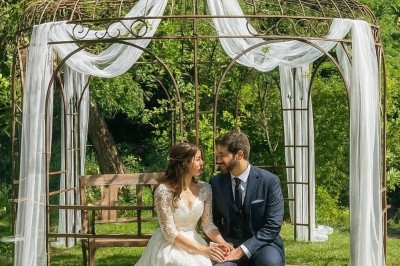 Rivière bordée de rochers et de végétation sous un ciel bleu, avec une maison partiellement visible en arrière-plan.