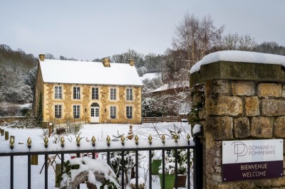 Chambre chaleureuse avec lits, canapé, fauteuils en osier, table basse et éclairage tamisé, décor rustique.