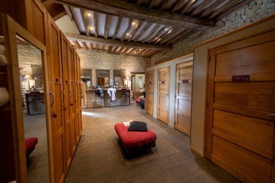 Chambre chaleureuse avec lits, canapé, fauteuils en osier, table basse et éclairage tamisé, décor rustique.