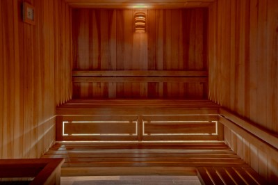 Chambre chaleureuse avec lits, canapé, fauteuils en osier, table basse et éclairage tamisé, décor rustique.