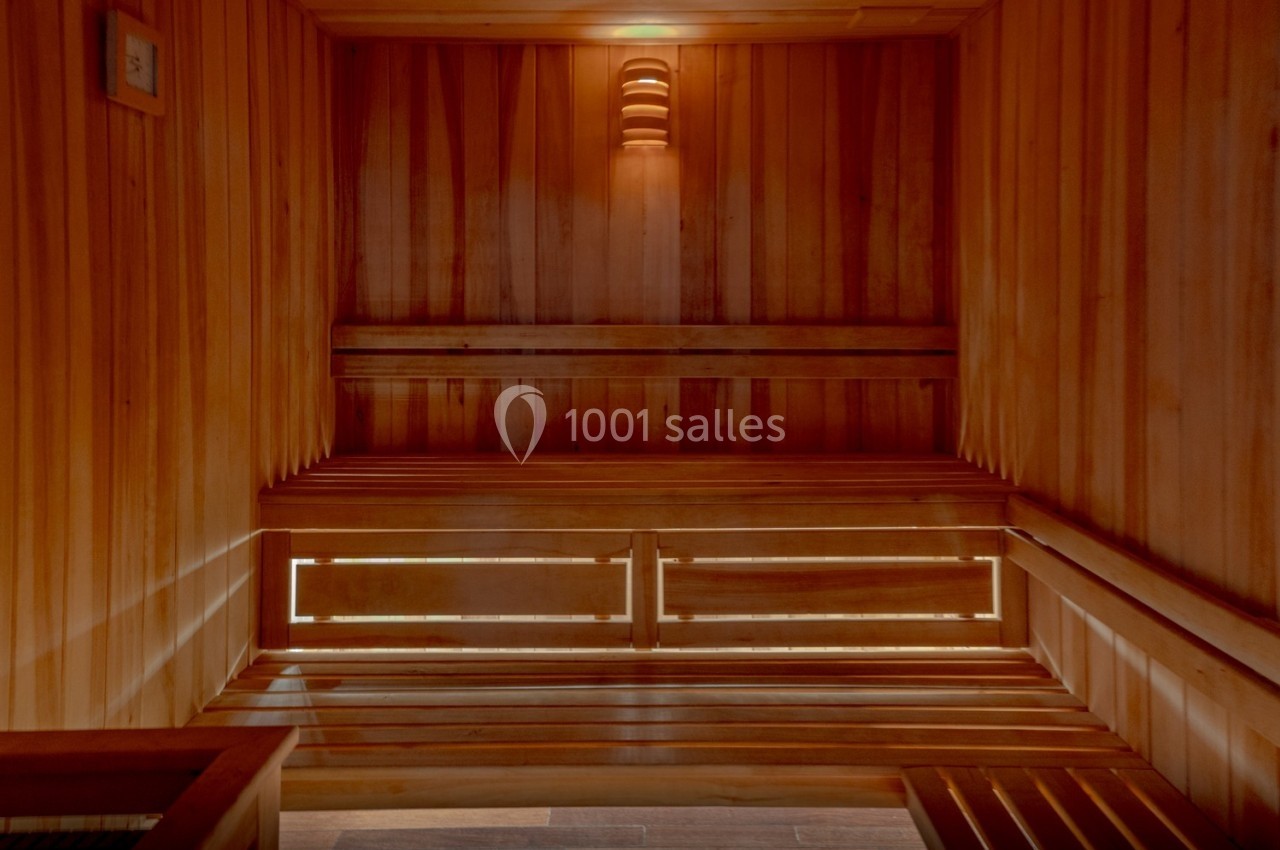 Intérieur d'un sauna en bois avec bancs superposés et éclairage tamisé.