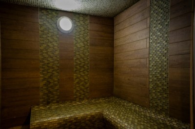 Chambre chaleureuse avec lits, canapé, fauteuils en osier, table basse et éclairage tamisé, décor rustique.