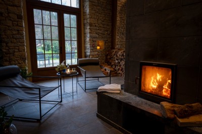 Chambre chaleureuse avec lits, canapé, fauteuils en osier, table basse et éclairage tamisé, décor rustique.