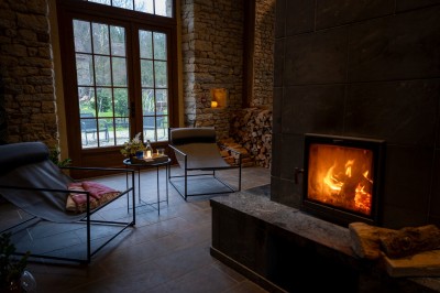 Chambre chaleureuse avec lits, canapé, fauteuils en osier, table basse et éclairage tamisé, décor rustique.