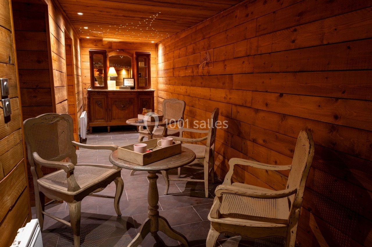 Espace chaleureux avec murs en bois, tables et chaises rustiques, éclairage tamisé et buffet en arrière-plan.