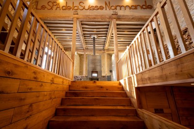 Chambre chaleureuse avec lits, canapé, fauteuils en osier, table basse et éclairage tamisé, décor rustique.