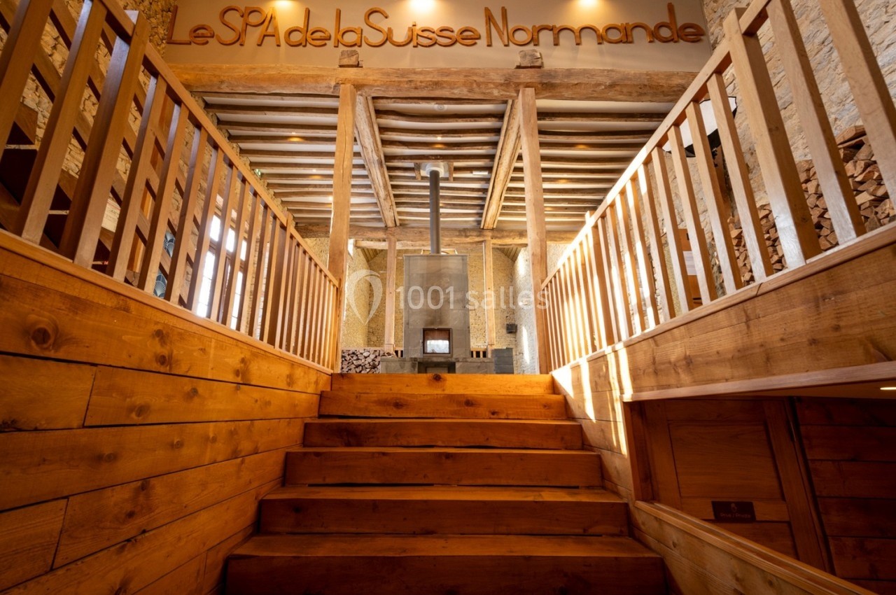 Escalier en bois menant à une entrée de spa avec des murs en pierre et une ambiance chaleureuse.
