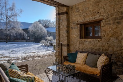 Chambre chaleureuse avec lits, canapé, fauteuils en osier, table basse et éclairage tamisé, décor rustique.