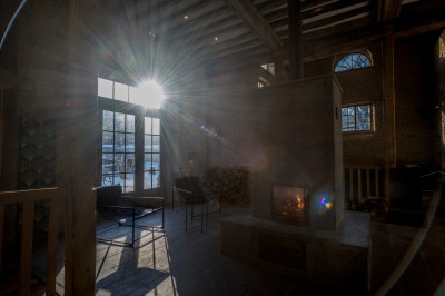 Chambre chaleureuse avec lits, canapé, fauteuils en osier, table basse et éclairage tamisé, décor rustique.