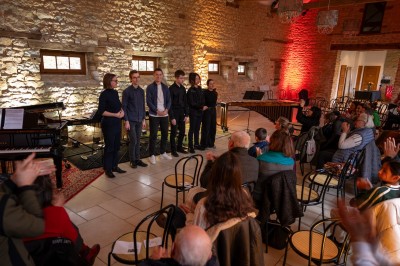 Chambre chaleureuse avec lits, canapé, fauteuils en osier, table basse et éclairage tamisé, décor rustique.