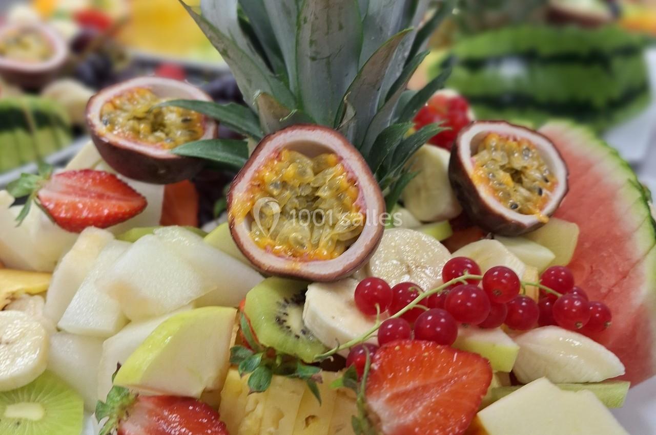 Assortiment de fruits frais comprenant ananas, orange, fraise, kiwi, groseille et fruit de la passion.