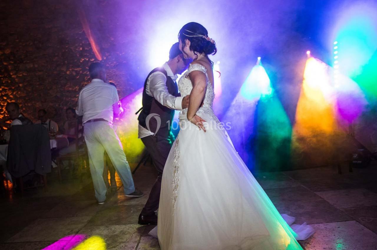 Un couple danse lors d'une soirée festive, éclairée par des lumières colorées et une ambiance animée.