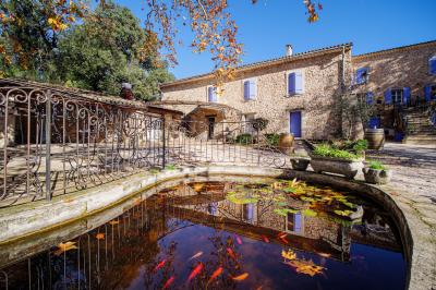 Mobilier de jardin blanc disposé sur une terrasse en gravier, avec vue sur des vignes et une forêt en arrière-plan.
