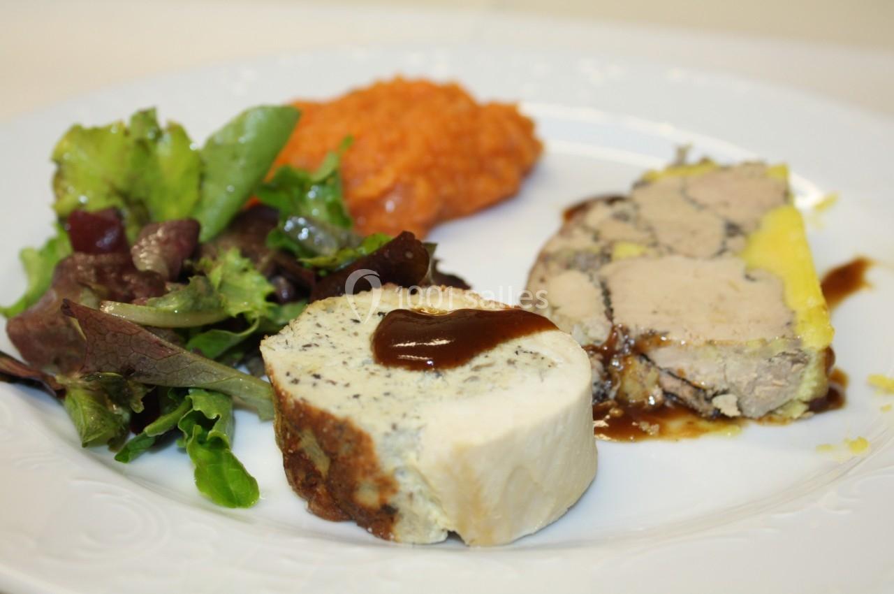 Assiette composée de foie gras, salade verte, purée de légumes et tranche de fromage avec sauce.