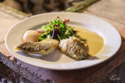 Mobilier de jardin blanc disposé sur une terrasse en gravier, avec vue sur des vignes et une forêt en arrière-plan.