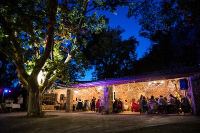 Mobilier de jardin blanc disposé sur une terrasse en gravier, avec vue sur des vignes et une forêt en arrière-plan.