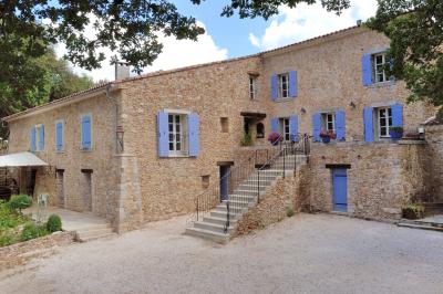 Mobilier de jardin blanc disposé sur une terrasse en gravier, avec vue sur des vignes et une forêt en arrière-plan.