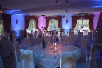 Mobilier de jardin blanc disposé sur une terrasse en gravier, avec vue sur des vignes et une forêt en arrière-plan.